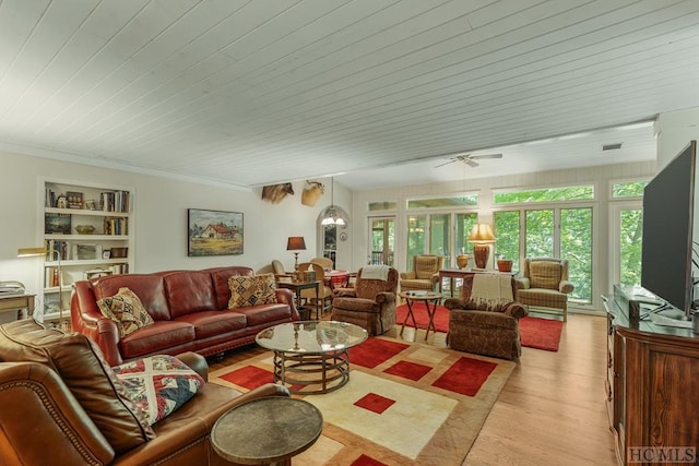 living room with crown molding, light hardwood / wood-style flooring, and built in shelves