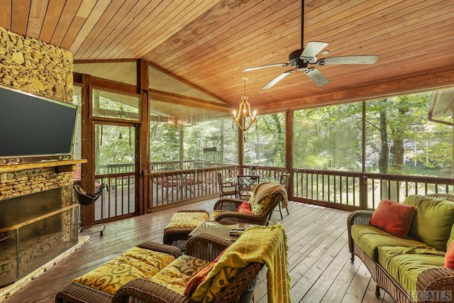 sunroom with vaulted ceiling, ceiling fan, wooden ceiling, and a stone fireplace