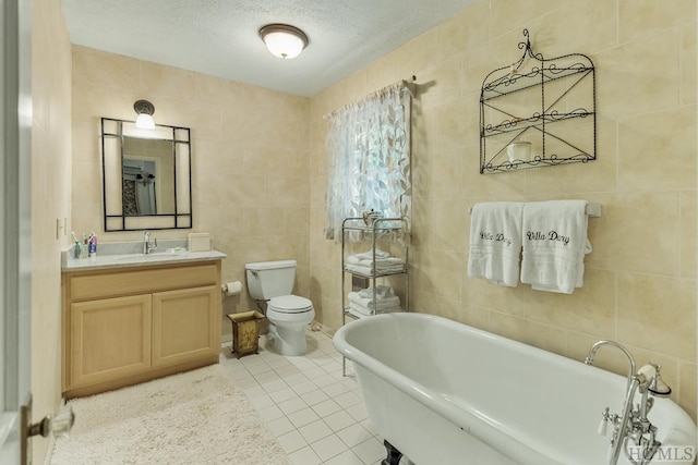 bathroom featuring toilet, a textured ceiling, a tub, tile walls, and tile patterned floors