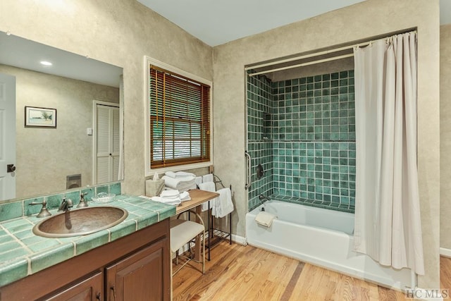 bathroom featuring wood-type flooring, vanity, and shower / bath combination with curtain