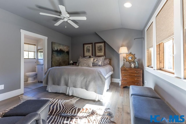 bedroom featuring connected bathroom, baseboards, lofted ceiling, and wood finished floors