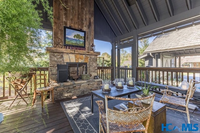 wooden terrace with an outdoor stone fireplace