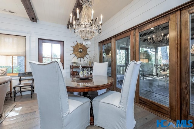 dining area with beamed ceiling, an inviting chandelier, light wood-style floors, and visible vents