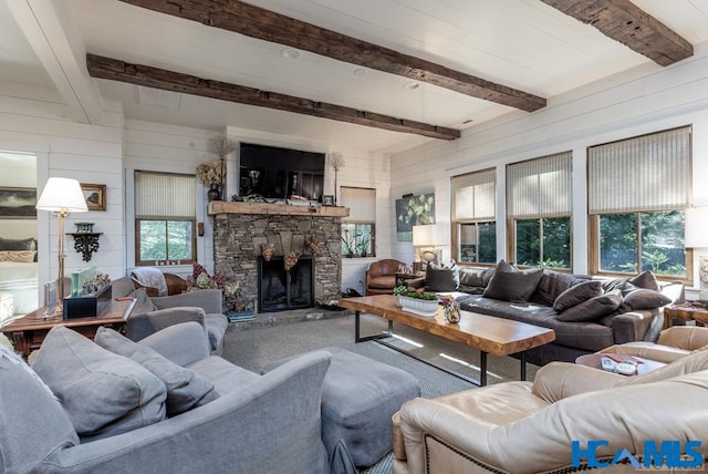 carpeted living area featuring a stone fireplace, beamed ceiling, and wood walls