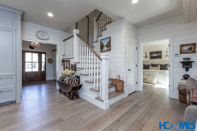 foyer entrance with stairway, wood walls, wood ceiling, recessed lighting, and light wood-style floors