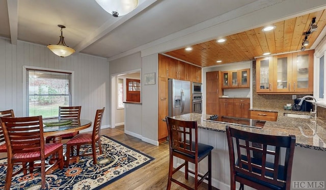 dining room with light wood-type flooring, beam ceiling, sink, and wooden ceiling