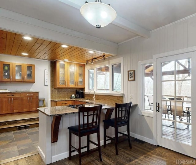 kitchen featuring a breakfast bar, decorative light fixtures, wooden ceiling, kitchen peninsula, and beamed ceiling