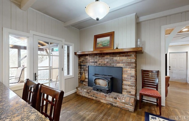 living room with beam ceiling, dark wood-type flooring, and a wood stove