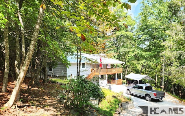 view of front of house with a detached carport, a wooden deck, driveway, and stairway