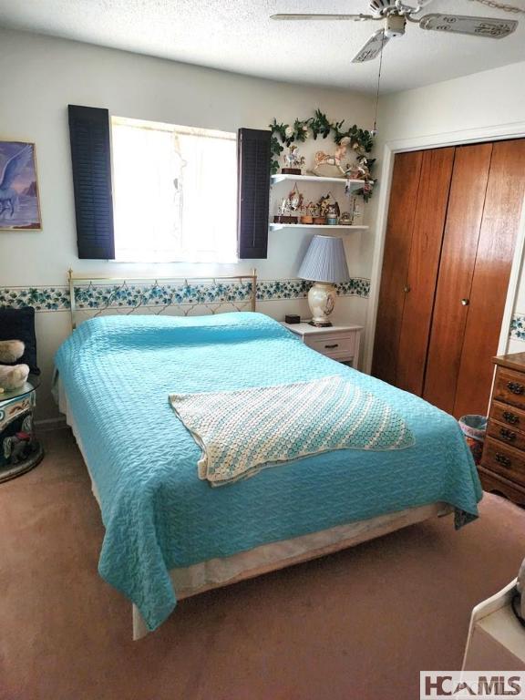 carpeted bedroom featuring a ceiling fan and a closet