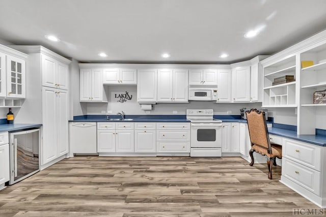 kitchen with white cabinetry, white appliances, built in desk, and light wood-type flooring