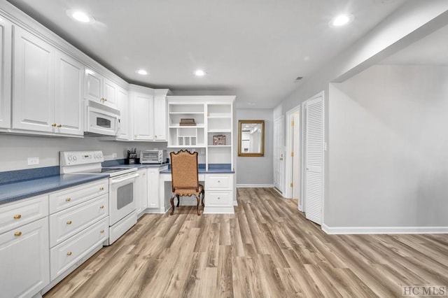 kitchen with white cabinetry, light wood-type flooring, built in desk, and white appliances