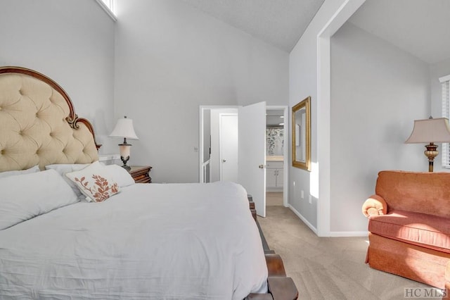 bedroom with ensuite bath, high vaulted ceiling, and light carpet