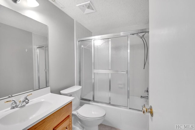 full bathroom featuring toilet, vanity, shower / bath combination with glass door, and a textured ceiling