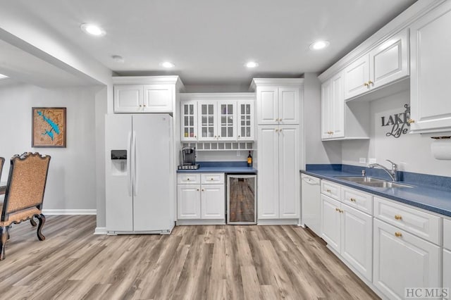 kitchen with white cabinetry, sink, light wood-type flooring, wine cooler, and white appliances