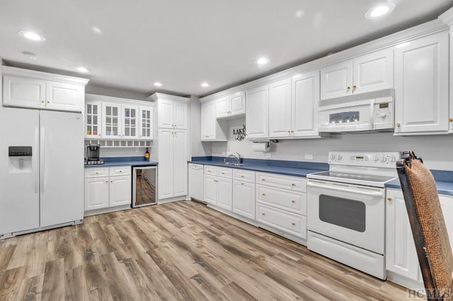 kitchen featuring sink, white appliances, wine cooler, white cabinets, and light wood-type flooring