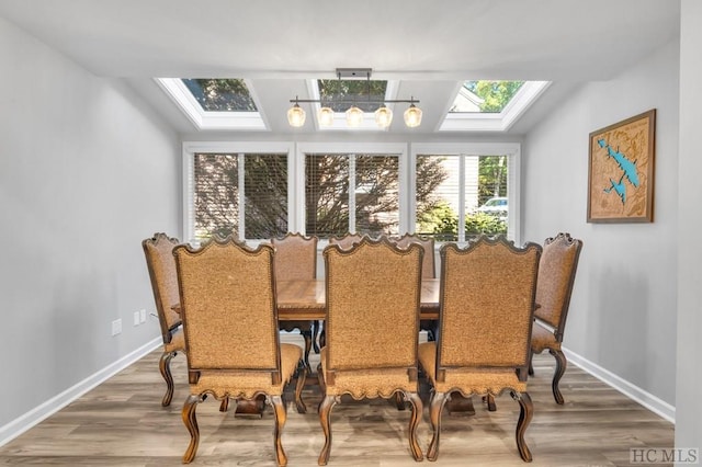 dining space with wood-type flooring and vaulted ceiling with skylight