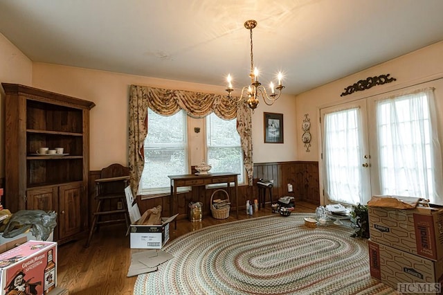 sitting room featuring french doors, wooden walls, a chandelier, and dark wood-type flooring