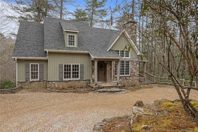 view of front of home featuring fence, stone siding, and roof with shingles