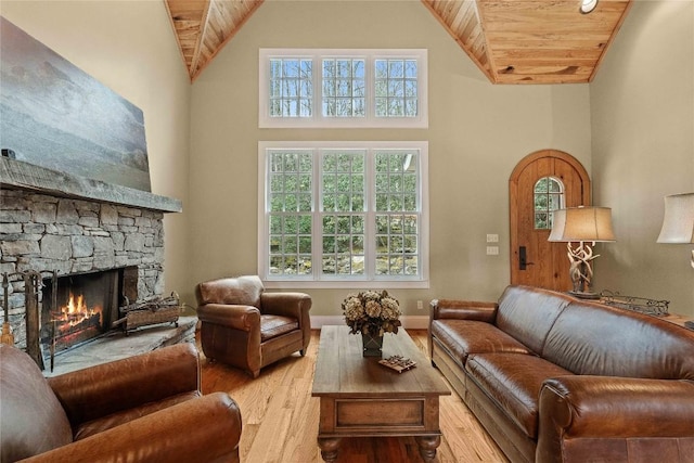 living area with high vaulted ceiling, a stone fireplace, wood ceiling, and wood finished floors