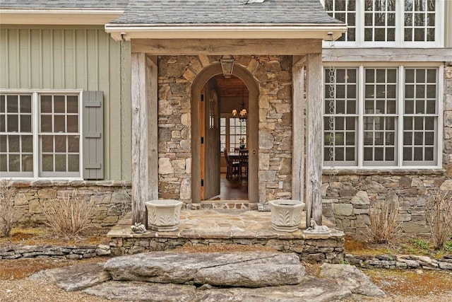 property entrance with stone siding and a shingled roof