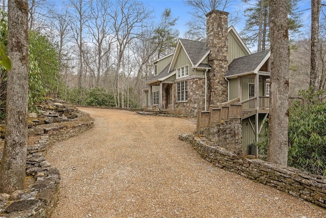 view of home's exterior with stone siding, a chimney, and roof with shingles