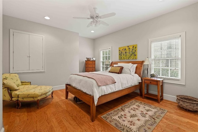 bedroom with baseboards, multiple windows, and light wood-style flooring