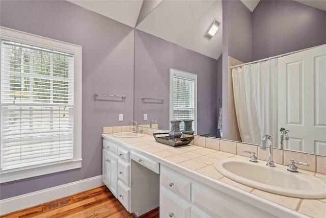 bathroom featuring a sink, visible vents, lofted ceiling, and wood finished floors