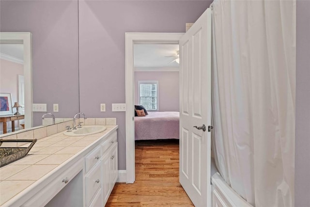 full bath with ornamental molding, a ceiling fan, wood finished floors, ensuite bath, and vanity