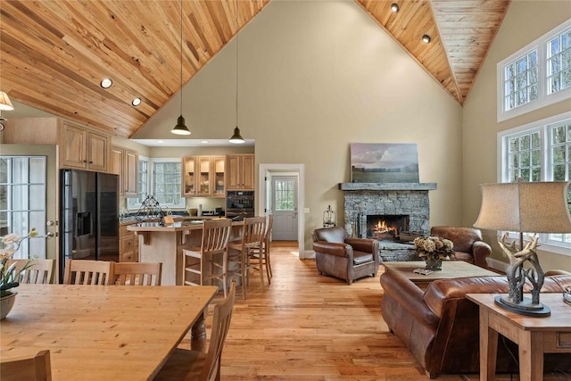 living area with high vaulted ceiling, light wood-style flooring, recessed lighting, a fireplace, and wood ceiling