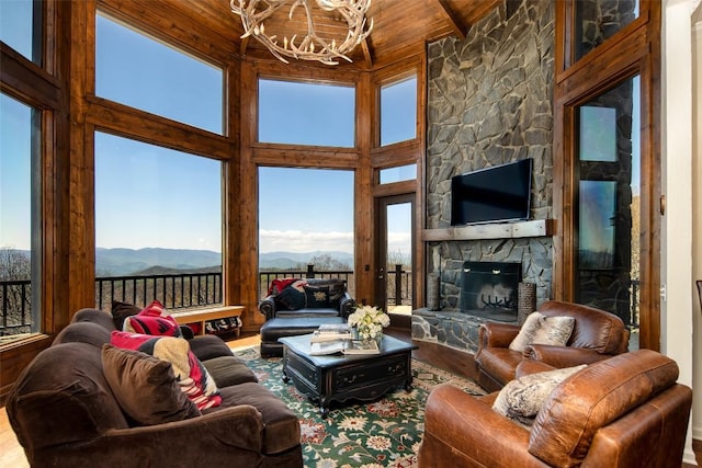 living area with wood finished floors, wooden ceiling, healthy amount of natural light, and a chandelier