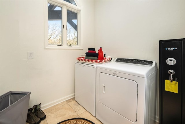 clothes washing area with independent washer and dryer, light tile patterned floors, and baseboards