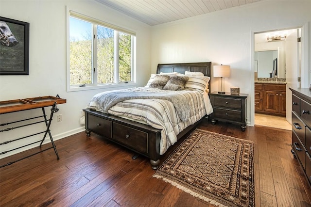 bedroom featuring ornamental molding, dark wood-style floors, a sink, connected bathroom, and wood ceiling