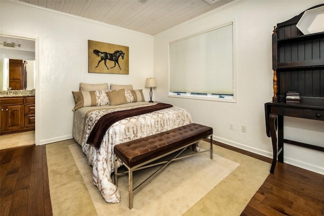 bedroom with wood finished floors, crown molding, baseboards, wooden ceiling, and connected bathroom