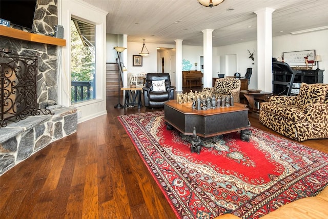 living area featuring decorative columns, a fireplace, hardwood / wood-style floors, stairs, and wooden ceiling