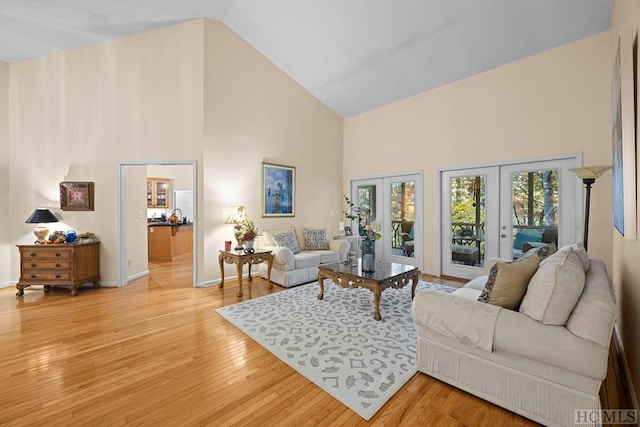 living room with high vaulted ceiling, french doors, and light wood-type flooring