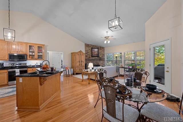 dining room with high vaulted ceiling, light hardwood / wood-style floors, sink, and ceiling fan