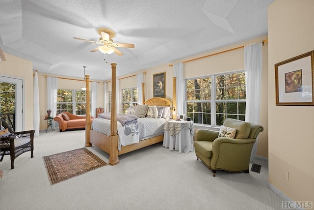 carpeted bedroom with a textured ceiling, ceiling fan, and a tray ceiling