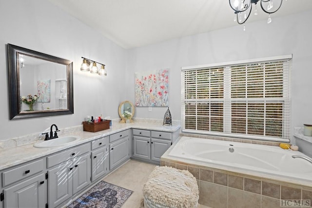 bathroom with an inviting chandelier, vanity, tiled bath, and tile patterned flooring