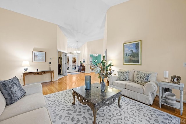 living room featuring high vaulted ceiling, hardwood / wood-style floors, and a chandelier