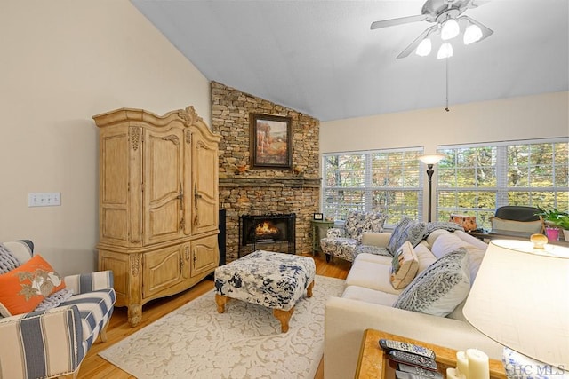 living room with high vaulted ceiling, light hardwood / wood-style flooring, ceiling fan, and a stone fireplace