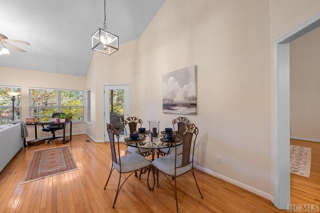 dining space featuring ceiling fan with notable chandelier, high vaulted ceiling, and light hardwood / wood-style floors