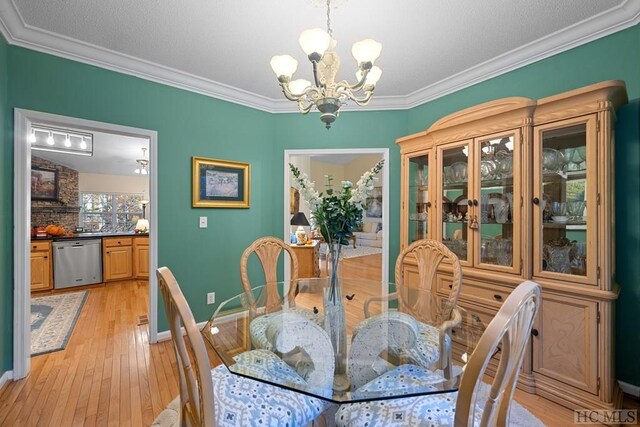 dining space with crown molding, a chandelier, and light wood-type flooring