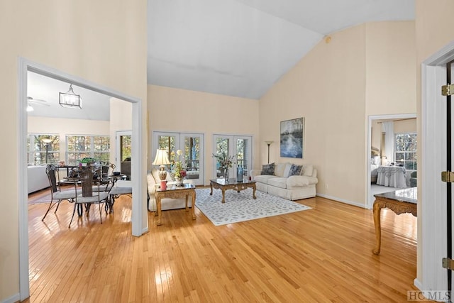 living room with light hardwood / wood-style flooring, high vaulted ceiling, and french doors