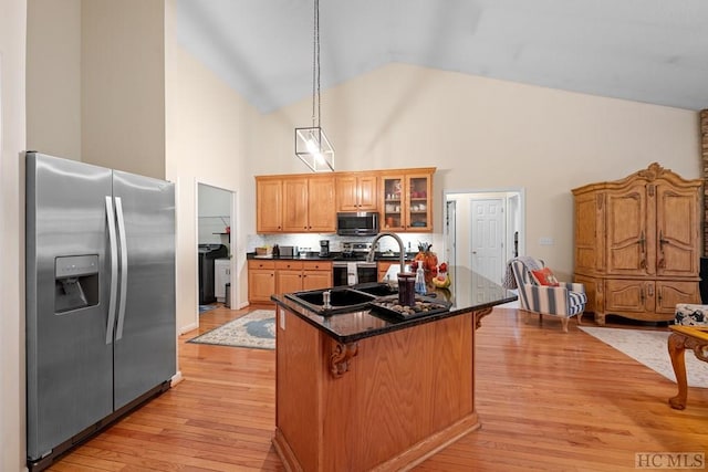 kitchen featuring high vaulted ceiling, a kitchen breakfast bar, stainless steel appliances, light hardwood / wood-style floors, and backsplash