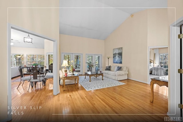 living room with wood-type flooring, high vaulted ceiling, and french doors