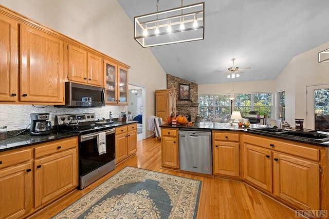 kitchen with sink, light hardwood / wood-style flooring, backsplash, stainless steel appliances, and decorative light fixtures