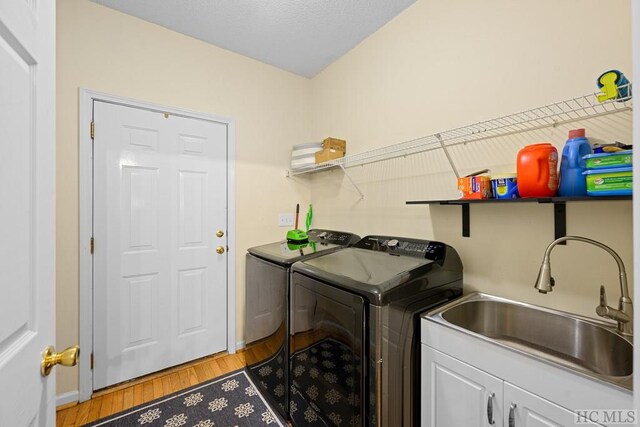 laundry area with sink, light hardwood / wood-style flooring, cabinets, and washing machine and clothes dryer