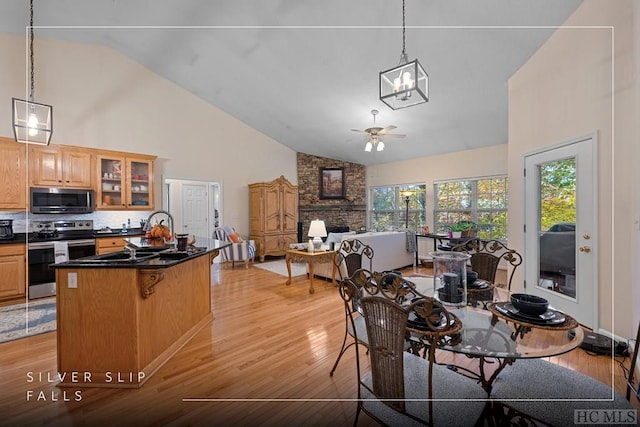 interior space with stainless steel electric stove, high vaulted ceiling, backsplash, a kitchen breakfast bar, and light hardwood / wood-style floors