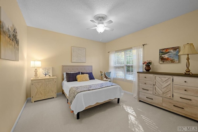 bedroom featuring light carpet, a textured ceiling, and ceiling fan